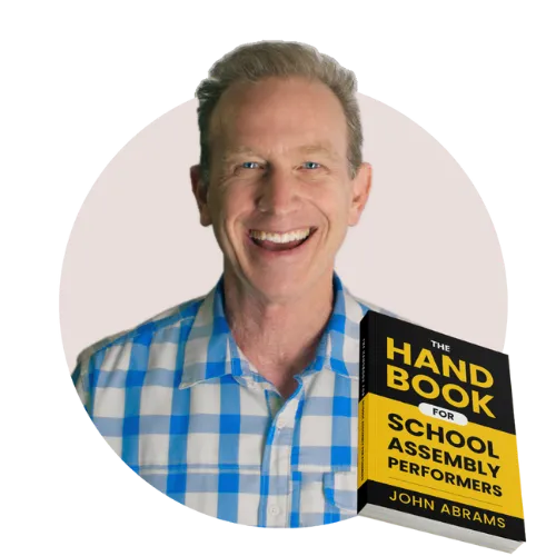 John Abrams smiling and holding his book, The Handbook for School Assembly Performers